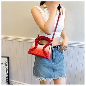 Détail du sac bandoulière rouge en cuir PU brillant avec une poignée incurvée ajourée