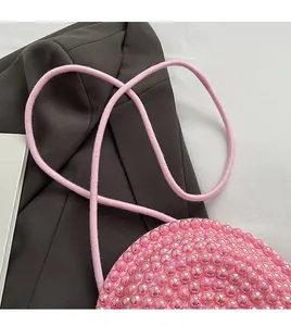 Dettaglio ravvicinato della borsa a tracolla con perline rosa e cinturino coordinato