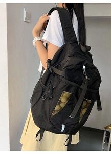Detail view of durable black nylon backpack with ergonomic straps and side mesh pocket