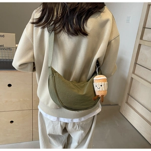 Olive green crescent canvas bag with a cute coffee cup plush charm shown on a model