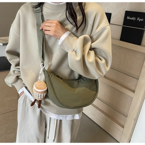 Olive green crescent nylon crossbody bag featuring a cute coffee cup plush charm on the side