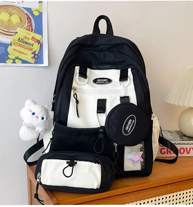 Detail of nylon backpack with mini pouches and cute white cat plush charm on a wooden desk