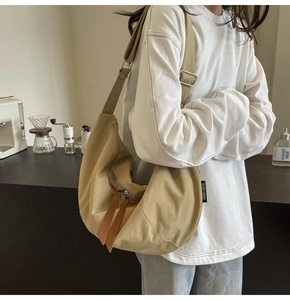 Detail of khaki crescent crossbody bag with adjustable strap and leather zipper puller