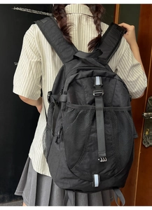 Detailed back view of a black nylon backpack with mesh pocket and wide shoulder straps