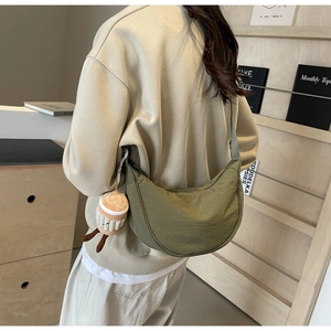 Detail of green crescent canvas crossbody bag with decorative plush cookie pendant
