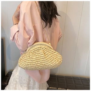 Detail of straw woven crossbody bag with gold chain strap on a vacation-style background