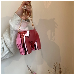 Detail of rose pink metallic creative butt-shaped handbag with golden snake chain