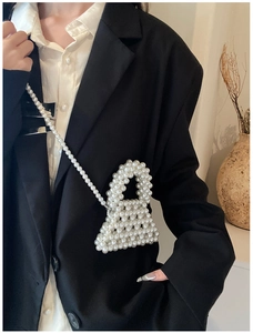 Close-up of handmade white pearl beaded mini crossbody bag on a model in a modern room