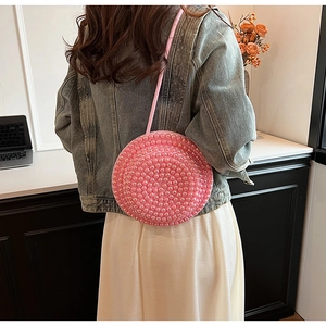 Vista dettagliata di una borsa a tracolla rotonda con perle rosa indossata da una modella