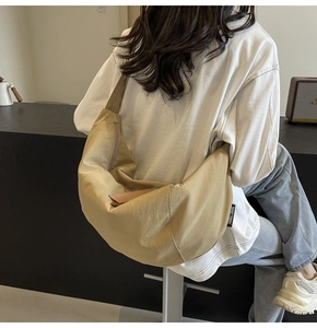 Detail of a khaki crescent crossbody bag worn by a model in a modern lifestyle setting