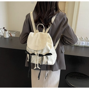 Close-up of white drawstring backpack featuring black bows and Nika embroidery