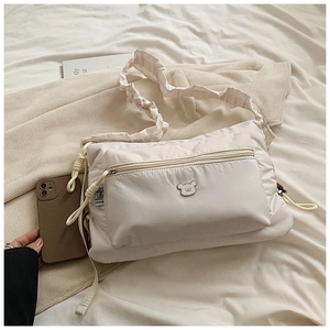 Quilted white nylon cloud crossbody bag with teddy bear charm and ruffled shoulder strap