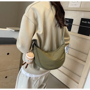 Detail of army green nylon crescent crossbody bag with a coffee plush charm and wide strap