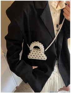 Detailed view of handmade white faux pearl crossbody bag on a professional suit