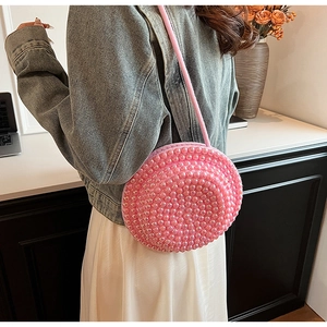 Dettaglio di una borsa a tracolla tonda rosa perlata fatta a mano con perline e tracolla