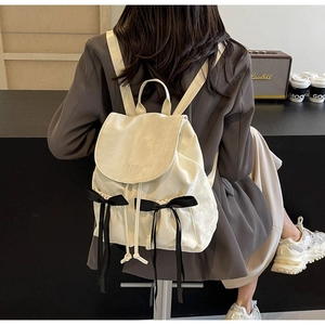 Detail view of cream PU leather backpack with black bows and embroidered Nika text