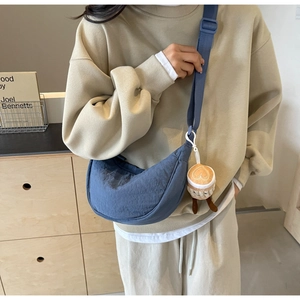 Detail of navy blue crescent nylon crossbody bag with cute plush pendant on a wide strap