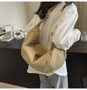 Detail of khaki crescent crossbody bag with adjustable strap in casual setting