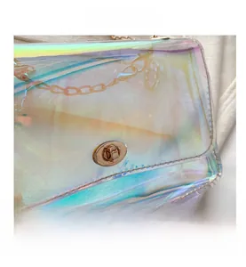 Detail of holographic PVC crossbody bag with a golden turn-lock closure and metal chain strap