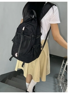 Close-up of black nylon backpack with functional pockets and white safety reflective strip