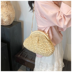 Detail of a straw woven cloud bag featuring metallic frame closure and gold chain strap