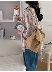Detailed side view of khaki nylon backpack on model in a cozy lifestyle setting