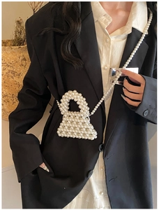 Detail view of handmade woven pearl mini bag with elegant crossbody chain on a model
