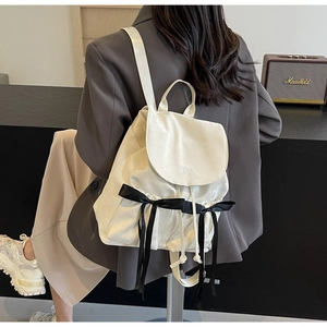 Detail of white PU backpack featuring black ribbon bows and Nika embroidery detail