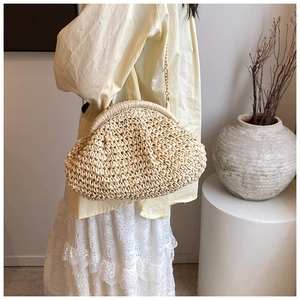Detailed view of handmade woven straw crossbody bag with gold metal chain strap for women
