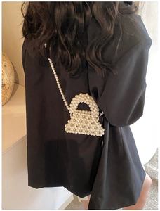 Detail of handcrafted white pearl crossbody bag with beaded texture and elegant strap