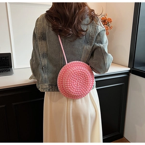 Dettaglio posteriore della modella con borsa a tracolla rotonda rosa decorata con perle