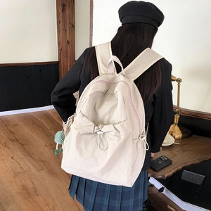 Dettaglio dello zaino in nylon bianco sporco con tasca a coulisse e ciondolo di peluche