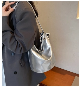 Detail of silver metallic PU shoulder bag featuring pearl bow and metal buckle design