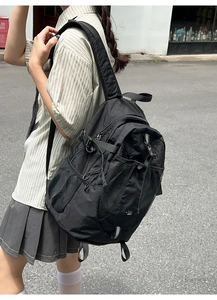 Side view of a black nylon functional backpack with adjustable buckles in a street setting