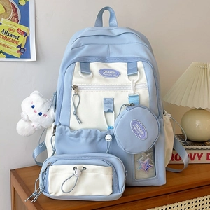 Three-piece light blue and white nylon backpack set with plush cat charm on wooden shelf