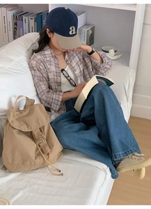 Close-up of a large khaki nylon backpack styled with a casual urban outfit in a library
