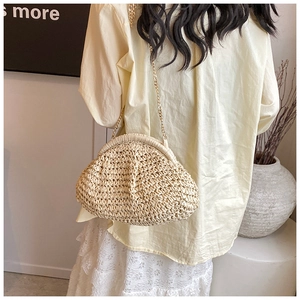 Detail of beige straw cloud bag with golden chain strap for summer minimalist look