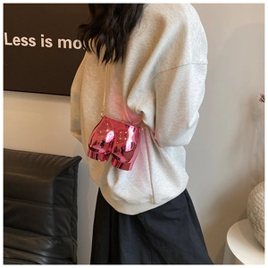 Detailed macro view of creative metallic pink butt-shaped crossbody bag with gold chain