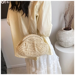 Macro detail of natural straw shell bag texture with golden chain strap on model