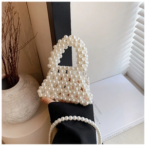 Detailed view of a handmade cream pearl beaded handbag with woven texture and top handle