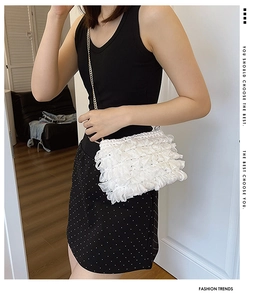 Detail of white pleated chiffon crossbody bag with delicate gold metal chain strap