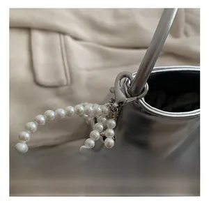 Detail of silver metallic purse featuring a lobster clasp and white pearl chain strap