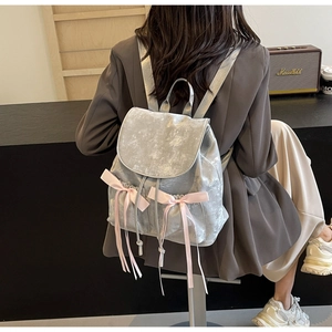 Macro detail of metallic silver PU backpack featuring pink satin bows and Nika logo