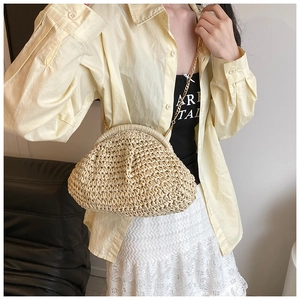 Detail of hand-woven straw crossbody bag with metal chain strap and vintage clasp closure
