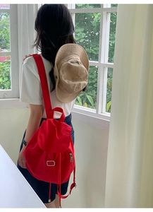 Detail of red nylon backpack with drawstring and metal buckles in casual styling