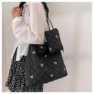 Detail of black quilted tote bag with pink bow embroidery and silver chain strap