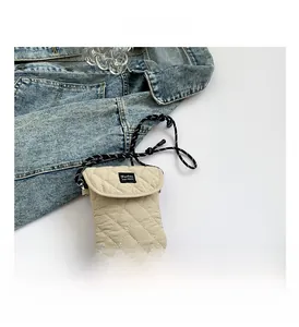 Detail of quilted beige mini crossbody bag with black and white woven rope shoulder strap
