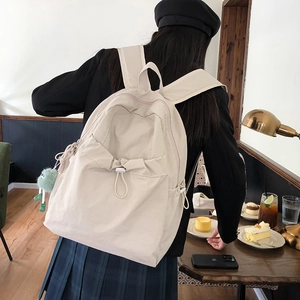 Dettaglio dello zaino in nylon crema con tasca con coulisse e ciondolo in peluche carino