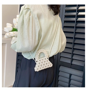 Detail of handcrafted pearl mini crossbody bag with glossy texture and pearl strap