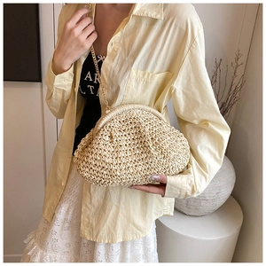 Detail of cream woven straw cloud bag featuring fine pleats and a slim gold metal chain strap